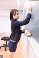 A woman in a business suit writing on a blackboard.