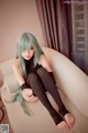 A woman with long green hair sitting on a couch.